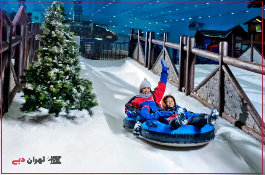 A woman with her child on a tube sliding through the snow at a ski resort in Dubai